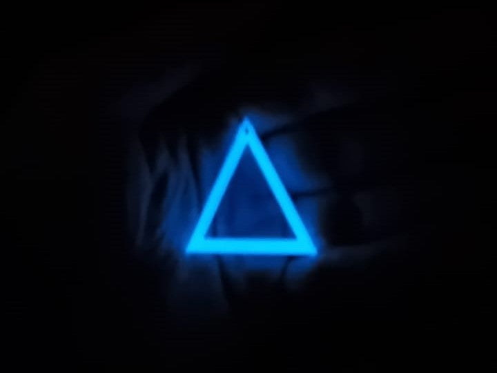 Blue to Blue Triangle earring In hand glowing in the dark