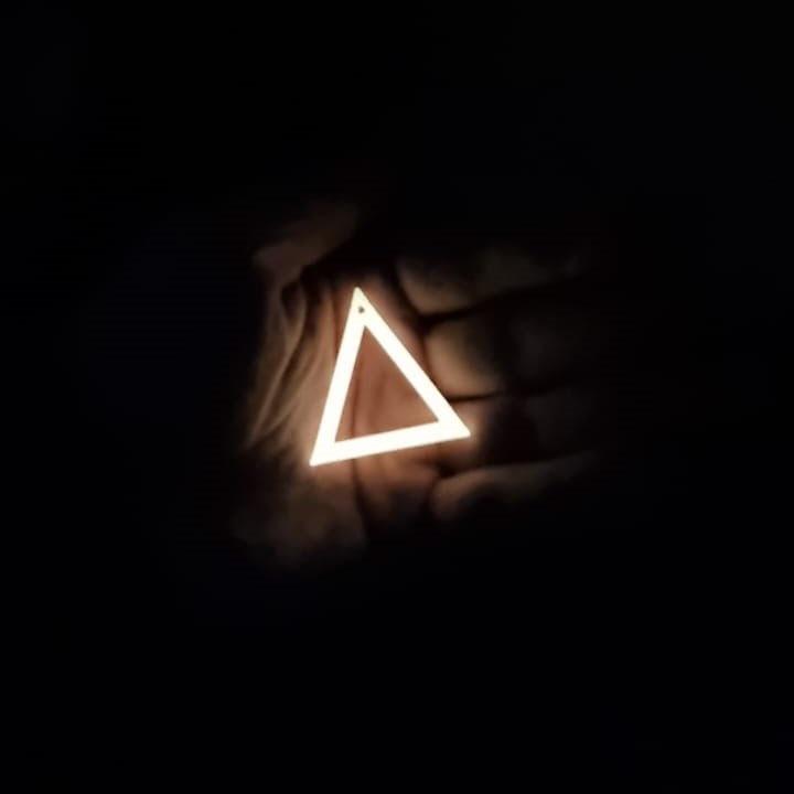 Pink to Yellow Triangle earring In hand glowing in the dark