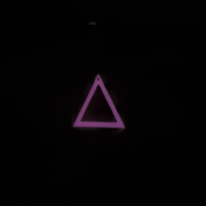 Pink to Pink Triangle earring In hand glowing in the dark