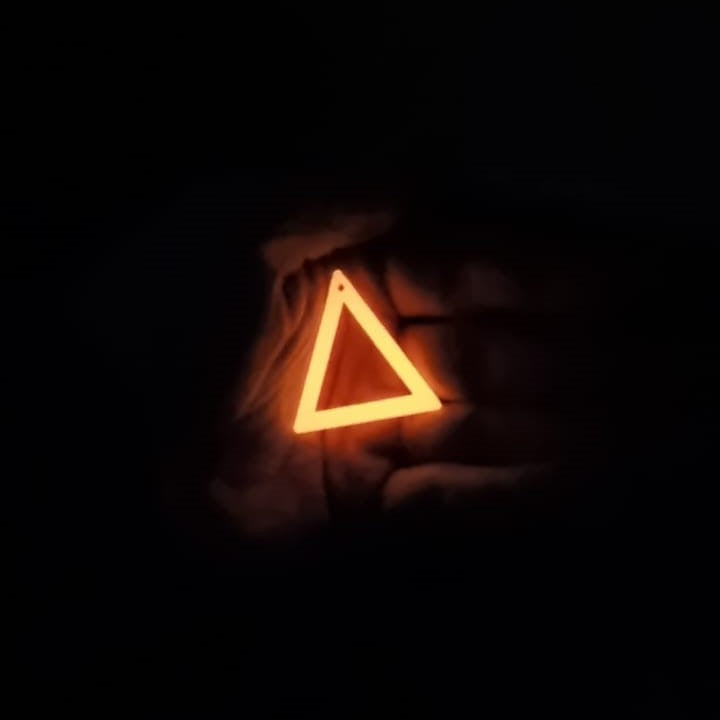 Red to Orange Triangle earring In hand glowing in the dark