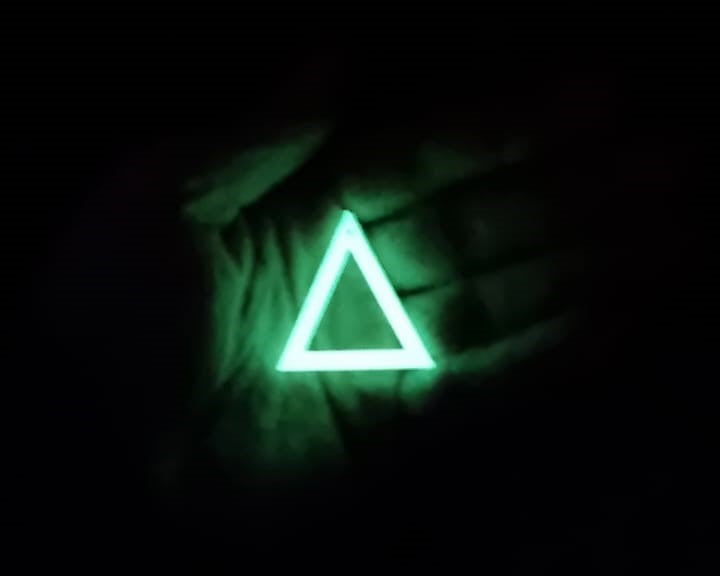 White to green Triangle earring In hand glowing in the dark