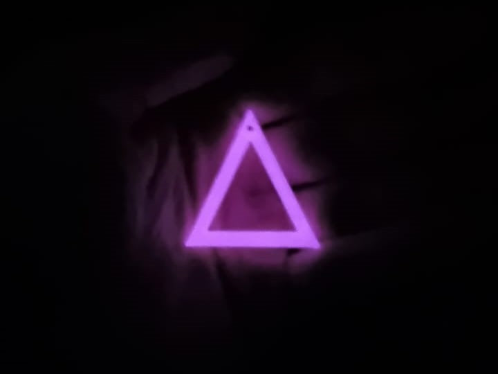 White to pink Triangle earring In hand glowing in the dark