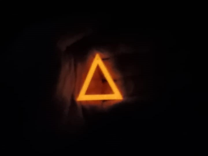 White to Yellow Triangle Earring In hand glowing in the dark